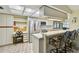 Well-lit kitchen with white cabinetry, stainless steel refrigerator, and a breakfast bar with seating at 1622 El Tair Trl, Clearwater, FL 33765