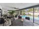 A covered patio features an outdoor dining table, lounge area, and lush landscaping surrounding the swimming pool at 1622 El Tair Trl, Clearwater, FL 33765