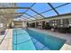 Inviting screened-in pool with a covered patio, bar seating, lounge chairs, and outdoor kitchen at 1622 El Tair Trl, Clearwater, FL 33765