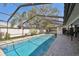 Relaxing screened-in pool area with a long in-ground pool, tiled patio, and partial outdoor kitchen at 1622 El Tair Trl, Clearwater, FL 33765