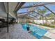A covered backyard pool area with an outdoor dining table, lounge area, and lush landscaping for privacy at 1622 El Tair Trl, Clearwater, FL 33765
