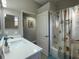 Well-maintained bathroom featuring a white vanity, white tub/shower with patterned curtain, and a decorative mirror at 18108 Ashton Park Way, Tampa, FL 33647