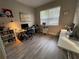 Well-lit home office with multiple workstations, hardwood floors, and a large window providing natural light at 18108 Ashton Park Way, Tampa, FL 33647