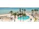 Beautiful pool area overlooking the beach with palm trees and lounge chairs at 200 1St Ave # 406, St Pete Beach, FL 33706