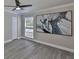 Bright bedroom with a ceiling fan, a window with blinds, gray walls, and light gray wood-look floors at 2011 S Carolina Ave, Tampa, FL 33629