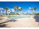 Outdoor pool with a paved patio area, surrounded by palm trees and a white fence with loungers at 2530 Gary Cir # 301, Dunedin, FL 34698
