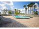 Outdoor pool with a paved patio area, surrounded by palm trees and a white fence with loungers at 2530 Gary Cir # 301, Dunedin, FL 34698