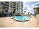 Outdoor pool with a paved patio area, surrounded by palm trees and a view of the condominium building at 2530 Gary Cir # 301, Dunedin, FL 34698