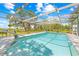 Beautiful screened-in pool with views of the surrounding landscape and clear blue skies, ideal for relaxation at 3041 Waterfall Dr, Spring Hill, FL 34608