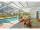 Relaxing screened-in pool area with comfortable seating, ceiling fan, and views of the lush backyard at 3041 Waterfall Dr, Spring Hill, FL 34608