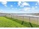 Green backyard features a beautiful lake view beyond the white picket fence at 3071 Marine Grass Dr, Wimauma, FL 33598