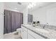 Bathroom with double sink vanity, granite countertop and shower with curtain at 3071 Marine Grass Dr, Wimauma, FL 33598