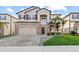 Charming two-story home featuring a stone facade, manicured lawn, and paver driveway at 3071 Marine Grass Dr, Wimauma, FL 33598