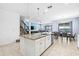 Open-concept kitchen featuring a large island with seating and view of the staircase at 3071 Marine Grass Dr, Wimauma, FL 33598
