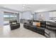 Spacious living area features leather sectional sofa, backyard access, and an open layout with kitchen views at 3071 Marine Grass Dr, Wimauma, FL 33598