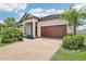 Home featuring a brick-paved driveway, a two-car garage, and lush landscaping at 31510 Cabana Rye Ave, San Antonio, FL 33576