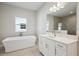 A bright bathroom with a freestanding tub, white cabinets, quartz countertops, and brushed nickel hardware at 35280 Big Hawk Ln, Zephyrhills, FL 33541