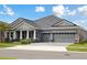 Beautiful home exterior with a three-car garage, gray roof, and nicely landscaped yard at 35280 Big Hawk Ln, Zephyrhills, FL 33541