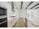 A modern kitchen featuring white cabinets, stainless steel appliances, quartz countertops, and dark wood beams at 35280 Big Hawk Ln, Zephyrhills, FL 33541