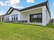 Home's backyard featuring a covered patio with sliding glass doors, green grass, and professional landscaping at 35571 Stableton Ln, Zephyrhills, FL 33541