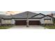 New construction duplex with wood garage doors, stone accents, and a tile roof during golden hour at 35571 Stableton Ln, Zephyrhills, FL 33541