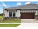 New construction home featuring a tile roof, wood garage door, and stone accents with a professionally landscaped yard at 35571 Stableton Ln, Zephyrhills, FL 33541