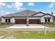 New construction townhome with a gray roof, two-car garage, and stone facade at 35571 Stableton Ln, Zephyrhills, FL 33541