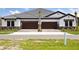 Charming exterior featuring stone accents, dark wood garage doors and a well-manicured lawn at 35579 Stableton Ln, Zephyrhills, FL 33541
