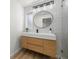 Modern bathroom vanity with light wood cabinets, white countertop, and round mirror at 3801 Dr Martin Luther King Jr N St, St Petersburg, FL 33703