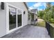 View of outdoor balcony with sliding glass doors and black metal railing overlooking the wooded backyard at 4522 Majestic Hills Loop, Brooksville, FL 34601