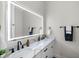 Modern bathroom with dual sinks, marble countertops, sleek black fixtures, and large illuminated mirror at 4522 Majestic Hills Loop, Brooksville, FL 34601