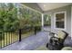 A covered patio has a view of a lush backyard with green trees; outdoor seating with green cushions invite relaxation at 4522 Majestic Hills Loop, Brooksville, FL 34601