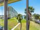 Scenic view from the balcony overlooking a grassy lawn, trees, and a glimpse of the waterway in the distance at 4700 Cove Cir # 301, St Petersburg, FL 33708