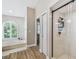 Bright bathroom featuring a soaking tub, a glass shower, and wood-look tile flooring at 5027 Cross Pointe Dr, Oldsmar, FL 34677