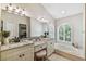 Bathroom with a large mirror, dual sinks, vanity, garden tub, and arched windows with plantation shutters at 5027 Cross Pointe Dr, Oldsmar, FL 34677