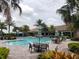 Resort-style community pool with tables, chairs, umbrellas and lounge seating surrounded by lush tropical landscaping at 5410 Morey Farms Loop, Palmetto, FL 34221