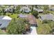 Aerial view of a home featuring a large driveway, a brown roof, solar panels, and mature landscaping at 5507 Nimitz Rd, New Port Richey, FL 34652