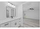 Bright bathroom with white cabinets, a modern vanity, a black framed mirror, and light gray vinyl floors at 5507 Nimitz Rd, New Port Richey, FL 34652