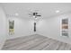 Bright bedroom showcasing gray vinyl floors, a ceiling fan, and a large window for natural light at 5507 Nimitz Rd, New Port Richey, FL 34652