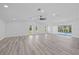 Spacious living room with a fan, recessed lights, sliding doors to the enclosed pool, and light wood-look floors at 5507 Nimitz Rd, New Port Richey, FL 34652