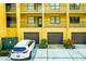 A yellow apartment building exterior with garages and a white car parked in the driveway at 5849 Park N St # 412, St Petersburg, FL 33709