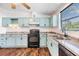 Bright kitchen features wooden floors, soft blue cabinetry, stainless steel sink and black appliances at 6036 110Th N Ave, Pinellas Park, FL 33782