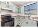 Bright kitchen features soft blue cabinetry, stainless steel sink, and black appliances at 6036 110Th N Ave, Pinellas Park, FL 33782