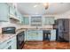 Bright kitchen features wooden floors, soft blue cabinetry, stainless steel sink and black appliances at 6036 110Th N Ave, Pinellas Park, FL 33782