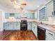 Bright kitchen features wooden floors, soft blue cabinetry, stainless steel sink and black appliances at 6036 110Th N Ave, Pinellas Park, FL 33782