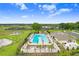 Aerial view of a community pool and amenity center with palm trees and manicured landscaping at 6384 Ten Acre Ct, Zephyrhills, FL 33541