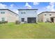 A home's spacious back yard features lush green grass and a screened-in patio at 6384 Ten Acre Ct, Zephyrhills, FL 33541