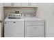 The laundry room includes a washer and dryer, and white cabinets for storage at 6384 Ten Acre Ct, Zephyrhills, FL 33541