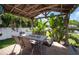 Covered patio with seating, surrounded by tropical landscaping, and a grassy lawn at 656 40Th Ne Ave, St Petersburg, FL 33703