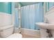 Cozy bathroom features a pedestal sink, and a tub with a blue shower curtain at 904 E Patterson St, Tampa, FL 33604
